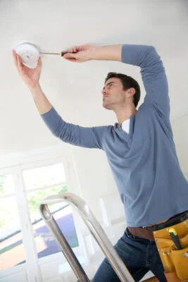 Photo depicting a qualified electrician installing a fire alarm