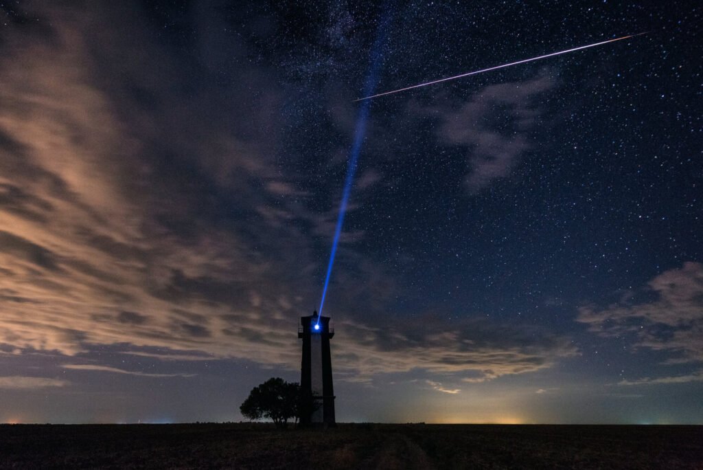 Amazing night landscape with starry sky, clouds and starlink satellites.
